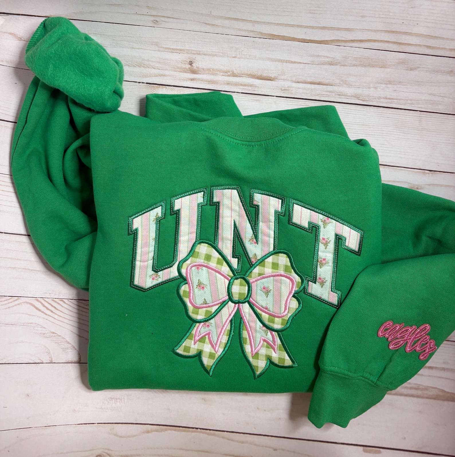 Green Eagles crewneck with floral UNT lettering, a gingham bow, and embroidered sleeve